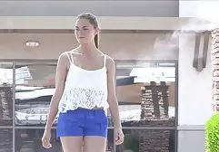 丰满的金发碧眼的巧妙地爱抚皮革沙发上的猫